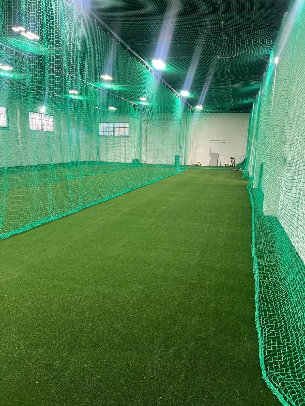 Long indoor turf lane separated from adjacent lanes by green netting